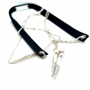 May include: A black choker necklace with a silver chain and a pendant with clear crystals. The necklace has a black band that goes around the neck and is connected to the chain.