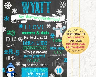 May include: A chalkboard style printable sign with a winter theme. It says "Wyatt My Winter ONEderland" and lists facts about the child, such as "23 pounds", "28.5 inches", "10 teeth", and "I love momma & dada, my dogs & cats, bath time, dancing, Mickey Mouse, paw patrol, music, my stuffed Simba". It also lists favorite foods: "Puffs Yogurt, Chicken Pb&J". The sign is decorated with snowflakes, penguins, and a polar bear.