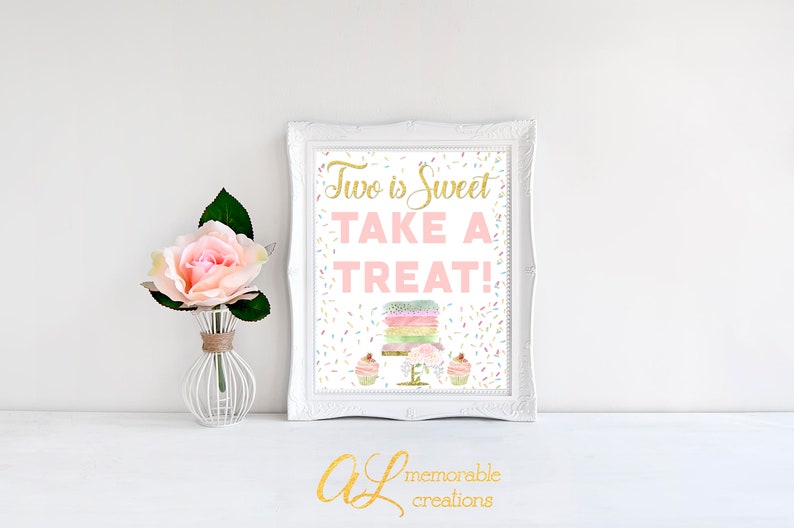 Może przedstawiać: Biały, oprawiony w ramę znak z tekstem "Two is Sweet Take a Treat!" w r&oacute;żowych i złotych literach. Znak zawiera akwarelową ilustrację tortu i babeczek z posypką.