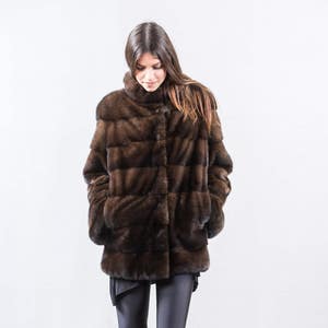 May include: A brown fur coat with a button closure. The coat is made of a soft, luxurious fur and has a classic, elegant style.