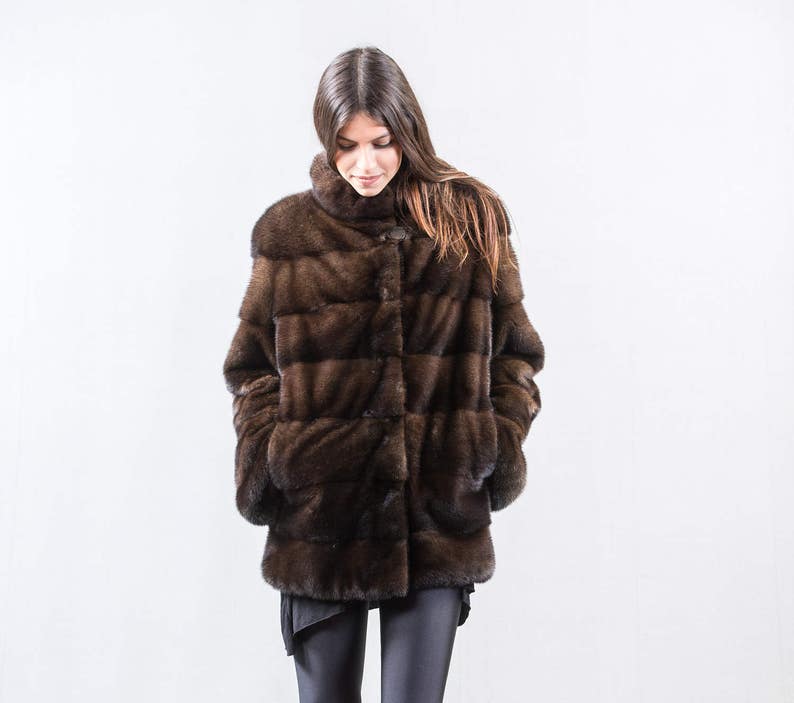 May include: A brown fur coat with a button closure. The coat is made of a soft, luxurious fur and has a classic, elegant style.