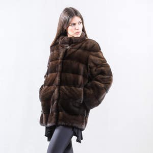May include: A brown fur jacket with a stand-up collar and horizontal stitching.