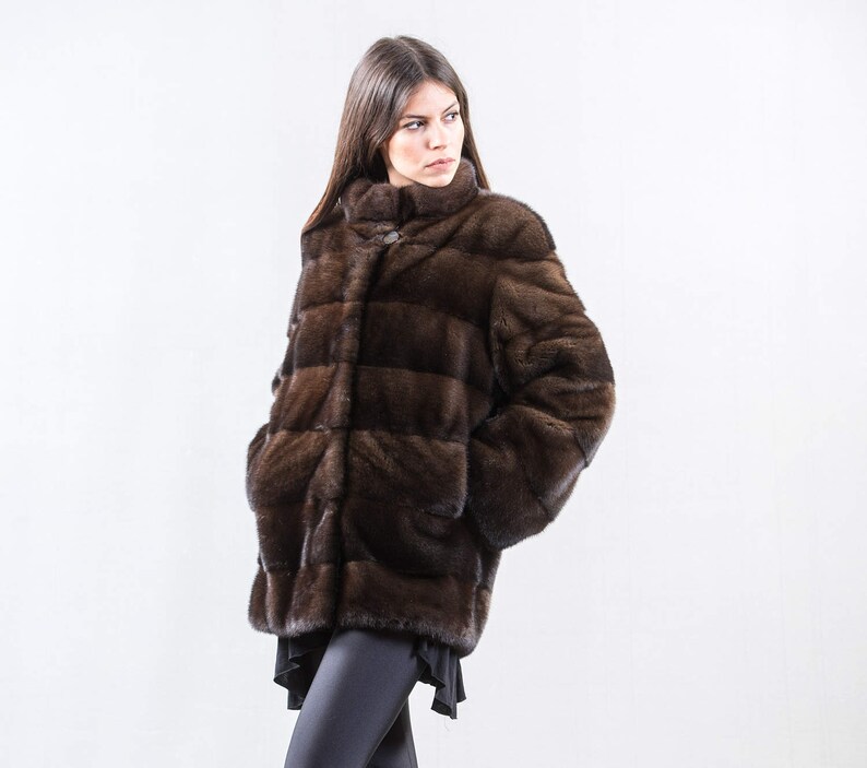 May include: A brown fur jacket with a stand-up collar and horizontal stitching.