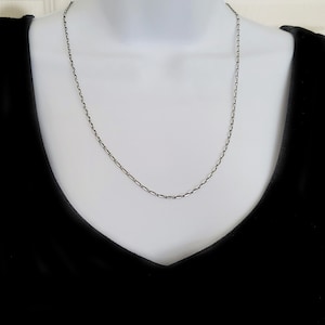 May include: A silver chain necklace on a mannequin. The chain is a simple, box style.