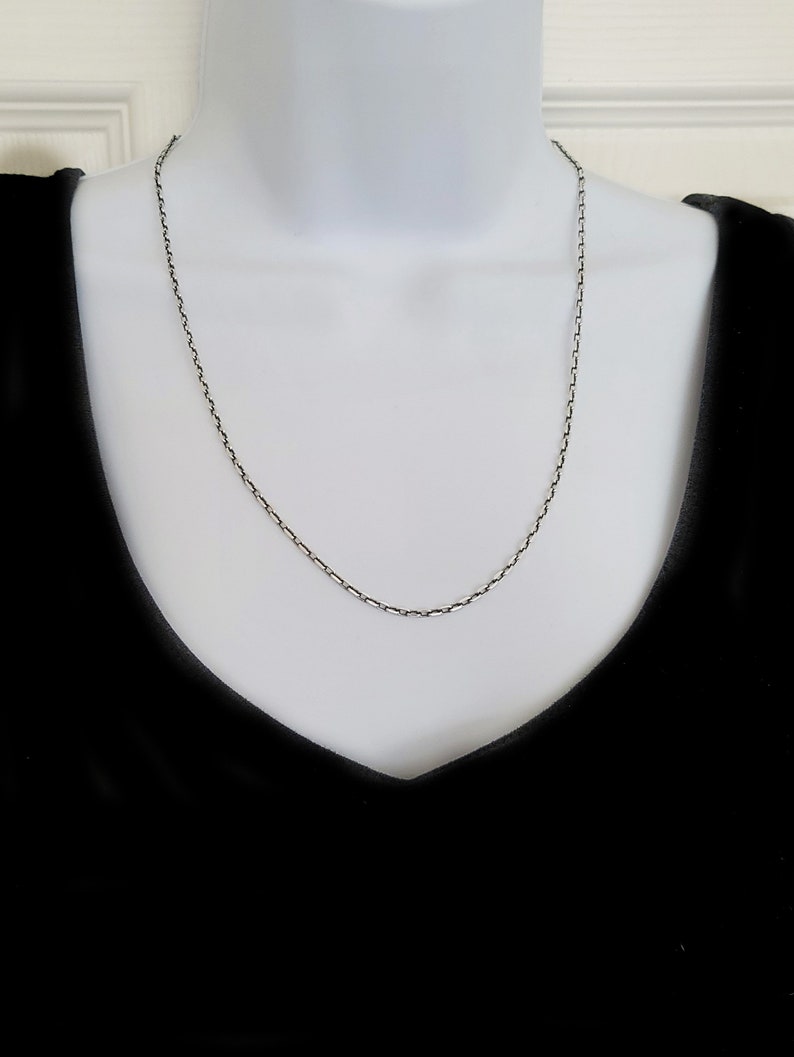 May include: A silver chain necklace on a mannequin. The chain is a simple, box style.