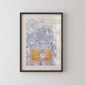 May include: A framed print of a vintage map of London with the postcode E3 in gold and pink lettering.