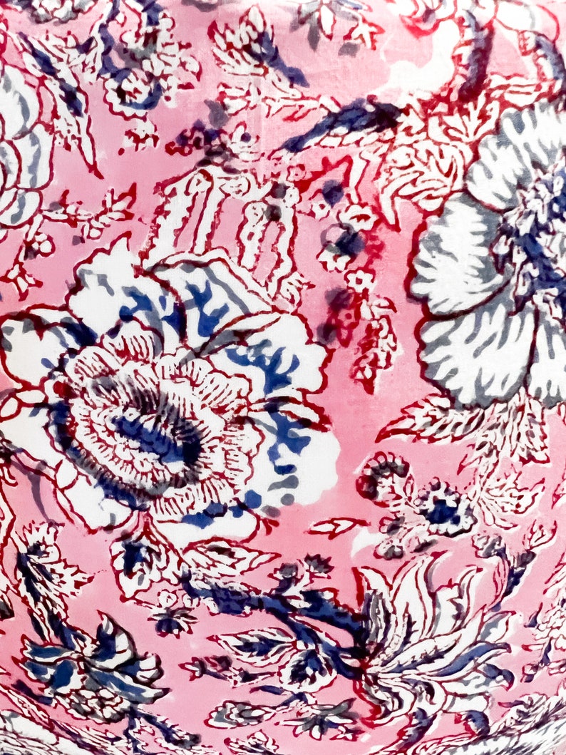 May include: Pink fabric with a white and blue floral pattern. The fabric has a vintage feel and is perfect for crafting projects.