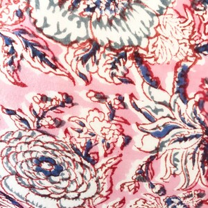 May include: Pink fabric with a floral pattern in shades of white, blue, and red. The flowers are stylized and have a vintage feel.