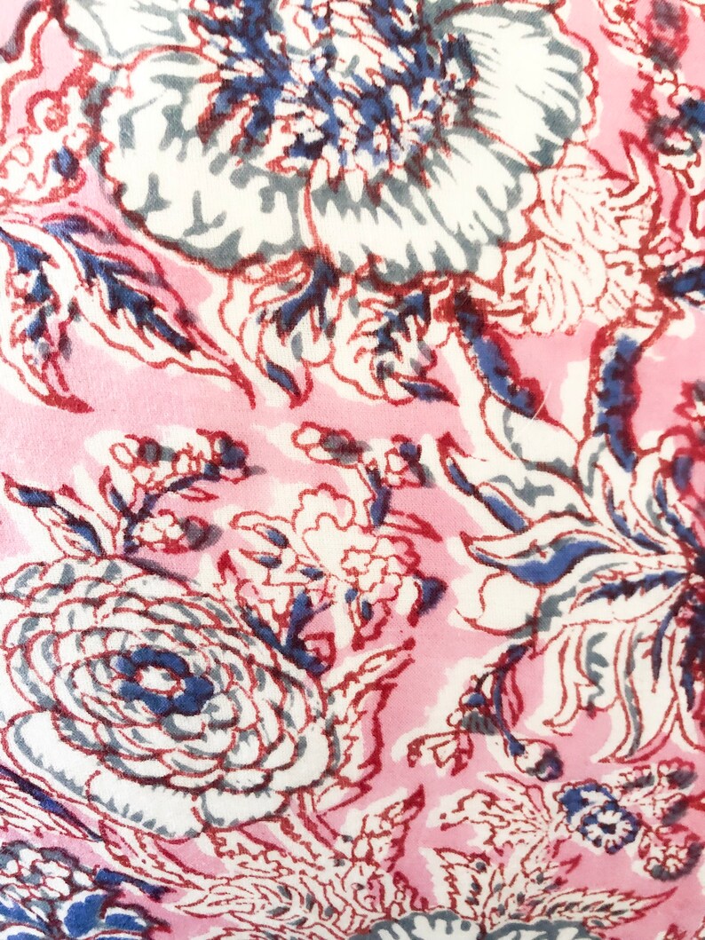 May include: Pink fabric with a floral pattern in shades of white, blue, and red. The flowers are stylized and have a vintage feel.