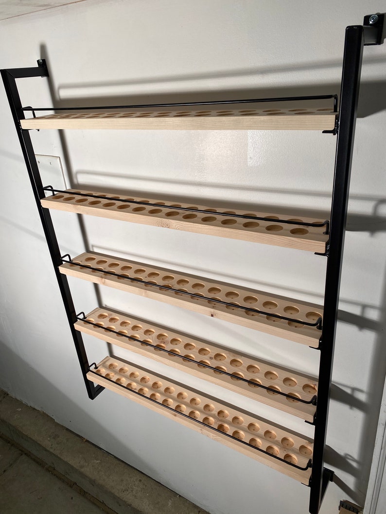 May include: A black metal wall-mounted shelf with four wooden shelves. Each shelf has a row of evenly spaced circular holes.