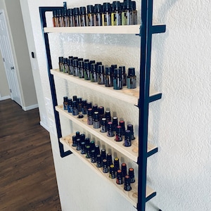 May include: A black metal wall-mounted shelf with four wooden shelves, each holding rows of small glass bottles. The bottles are filled with colorful liquids.