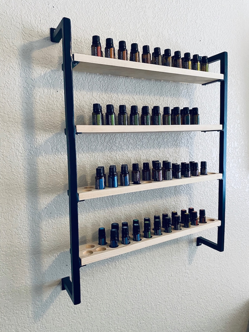 May include: A black metal wall-mounted shelf with four wooden shelves. The shelves are filled with small glass bottles of essential oils.