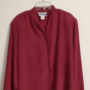 May include: A long-sleeved burgundy button-down blouse with a collar. The label reads "Guaranteed to be a Pendleton".