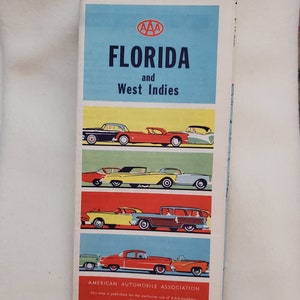 May include: A vintage AAA map of Florida and the West Indies. The map cover features a colorful illustration of cars driving on a road. The text "AAA Florida and West Indies" is printed in bold, white letters on a blue background. The text "American Automobile Association" is printed in black letters on a white background. The text "This map is published for the exclusive use of AAA members. It is not for sale." is printed in black letters on a white background.