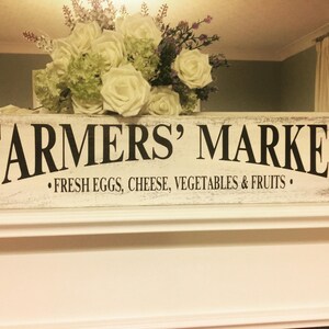 Peut inclure: Une enseigne en bois blanc avec des lettres noires qui disent "Farmers' Market" et "Fresh Eggs, Cheese, Vegetables & Fruits".