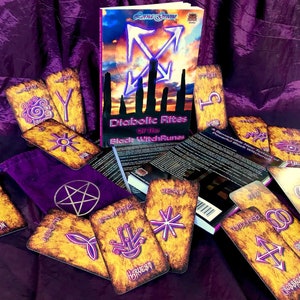 May include: A set of tarot cards with a purple background. The cards are spread out on a purple cloth. The cards have a gold and black design with a pentagram symbol. The cards are titled "Diabolic Rites of the Black Witch Runes".
