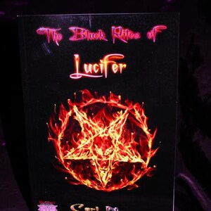 Puede incluir: Una portada de libro con fondo negro y el t&iacute;tulo "The Black Rites of Lucifer" en letras rosa y rojas. Un pentagrama ardiente se encuentra en el centro de la portada.