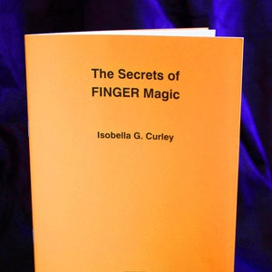 Pode incluir: Um livro laranja intitulado "The Secrets of FINGER Magic" de Isobella G. Curley. O livro tem a palavra "FINBARR" impressa no canto inferior direito.