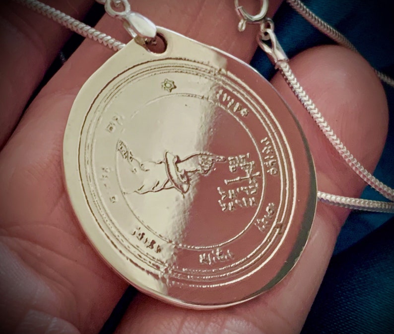 May include: Silver pendant necklace with a circular charm featuring an angel with wings and Hebrew text. The charm is surrounded by a circle of Hebrew text.