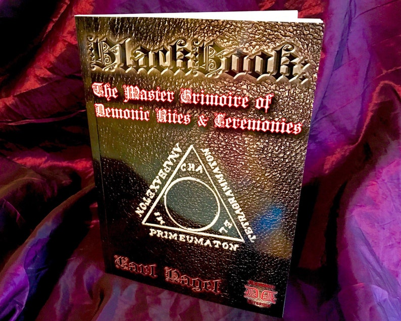 May include: A black leather-bound book titled "Black Book: The Master Grimoire of Demonic Rites & Ceremonies" with gold lettering and a gold embossed symbol on the cover. The symbol is a triangle with a circle inside and the words "TETRAGRAMMATON", "CHA", "PRIMEUMATON", "&Alpha;&Nu;&Alpha;&Rho;&Beta;&Alpha;&Chi;&Epsilon;&Tau;&Omicron;&Nu;", and "NO" written around the circle.