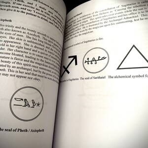 May include: A book page with black and white illustrations of symbols. The text on the page reads "The seal of Sarithaiel The alchemical symbol for fire".