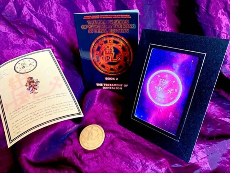 May include: A book titled "The Black Seals of Solomon the King Special Edition, Book 2: The Testament of Dantalion" with a gold seal on the cover. A framed print of a seal with a galaxy background. A gold coin with a seal on it.