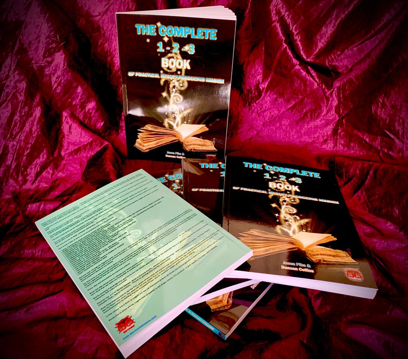 May include: A stack of three black and gold books titled "The Complete 1-2-3 Book of Practical Holistic Transformational Magic" by James Flie and Duncan Collins. The books are on a red velvet surface.