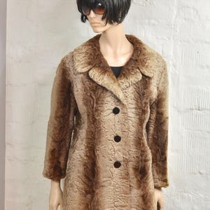 May include: A vintage brown faux fur coat with a textured pattern. The coat features a classic collar, three black buttons, and long sleeves. The coat is displayed on a mannequin.
