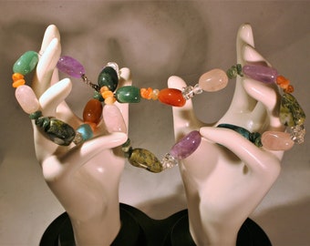 May include: A multi-colored gemstone necklace with beads of amethyst, rose quartz, green jade, turquoise, carnelian, and clear quartz.