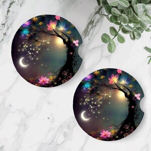 May include: Two round, colorful coasters with a whimsical design of a tree with glowing lights and flowers. The tree is silhouetted against a dark blue sky with a crescent moon. The coasters are perfect for adding a touch of magic to your home decor.