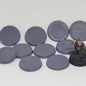May include: Ten gray plastic round bases for miniature figures, with a textured surface. The bases are approximately 25 mm in diameter.