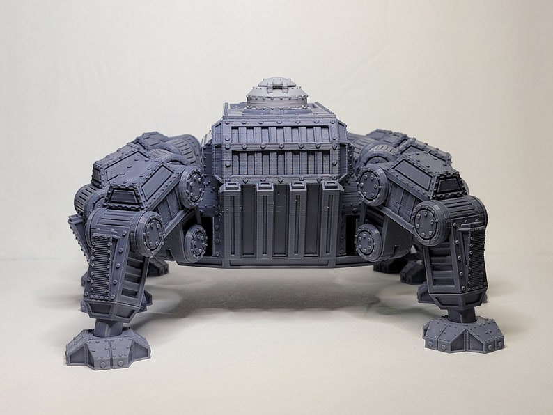 May include: A gray, detailed, 3D printed model of a four-legged, mechanical walker with a large, rectangular body and a small, round turret on top.