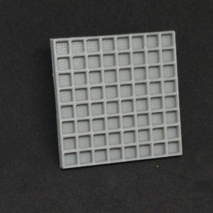May include: A gray plastic grid with a square pattern. The grid is made of small squares that are raised slightly from the surface.