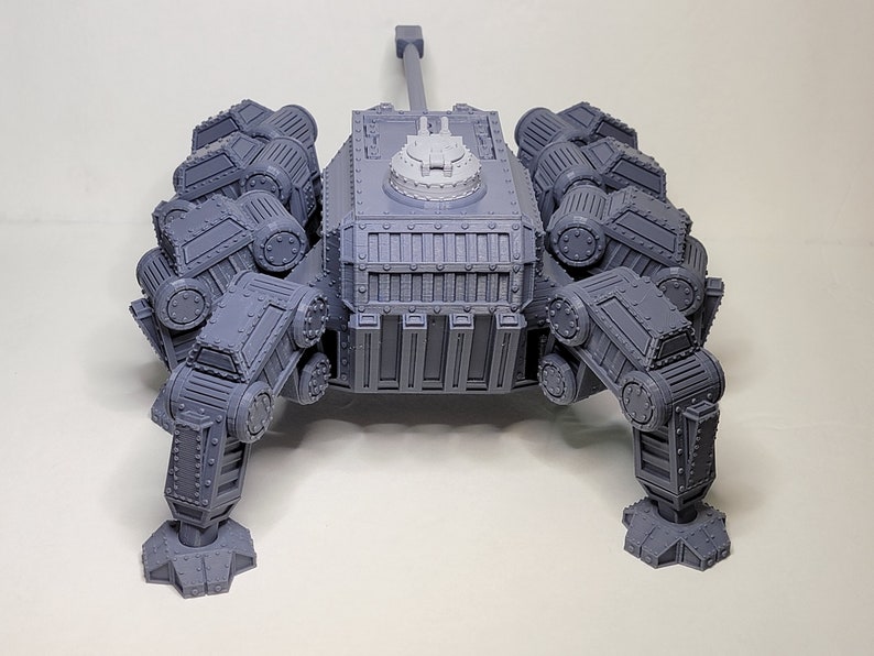 May include: A gray, 3D printed, multi-legged, tank-like model with a large cannon on top. The model has a detailed, textured surface and appears to be a miniature.