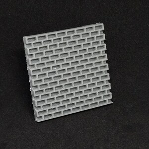 May include: A gray plastic brick wall texture sheet. The sheet is made of a textured plastic and has a brick pattern.