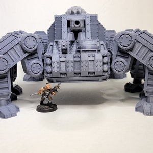 May include: A gray, detailed, articulated, multi-legged, mechanical walker with a large cannon on top. A small, painted, plastic figure of a soldier stands in front of the walker.