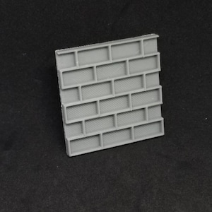 May include: A gray plastic brick wall texture sheet. The sheet is made to look like a brick wall with a rough texture.