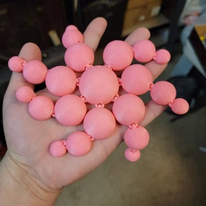 Puede incluir: Un modelo de molécula de color rosa impreso en 3D con forma de estrella.