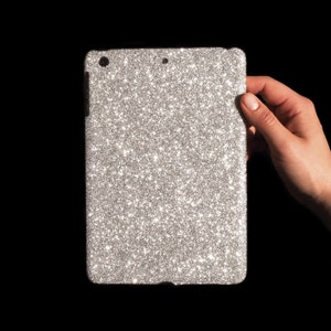 Könnte beinhalten: Eine iPad-Hülle aus silbernem Glitzer mit schwarzem Rand.