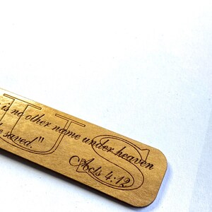 May include: A wooden bookmark with the text "There is no other name under heaven by which we are saved." and "Acts 4:12" engraved on it.