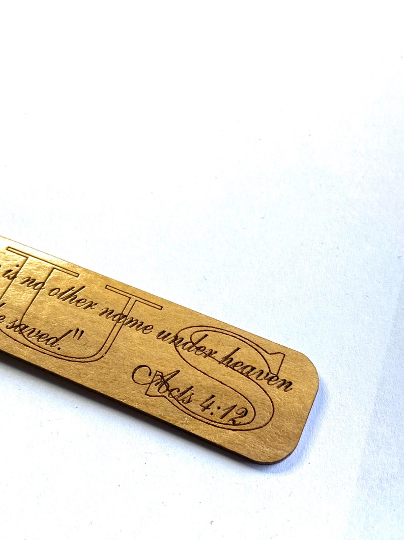 May include: A wooden bookmark with the text "There is no other name under heaven by which we are saved." and "Acts 4:12" engraved on it.