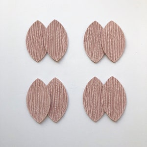 May include: Four pairs of pink leather earrings in the shape of a leaf. Each earring is made of two pieces of leather that are sewn together.