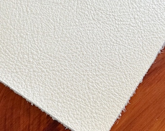 May include: A rectangular sheet of off-white material featuring a distinct pebbled, leather-like texture. The surface displays a consistent grain pattern across the entire piece, with visible frayed edges along the cut sides of the material.