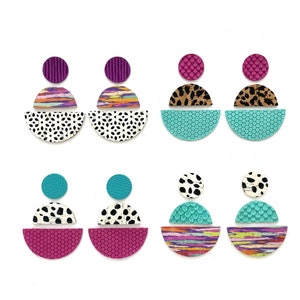 May include: Six pairs of colorful geometric earrings with a layered design. Each earring features a combination of turquoise, pink, white, and black patterned circles.
