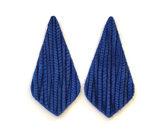 Peut inclure: Une paire de boucles d'oreilles en daim bleu en forme de goutte avec une surface texturée.