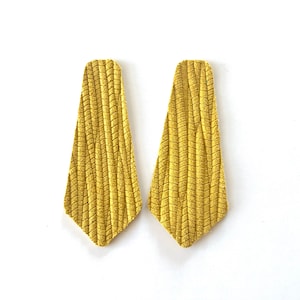 Puede incluir: Un par de pendientes de ante amarillo con un dise&ntilde;o texturizado y tejido. Los pendientes tienen forma de l&aacute;grima.