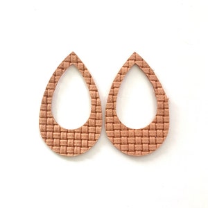 May include: A pair of light brown leather earrings with a woven texture and a teardrop shape.