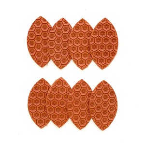 May include: Six brown leather leaves with a honeycomb pattern. The leaves are arranged in two rows of three.