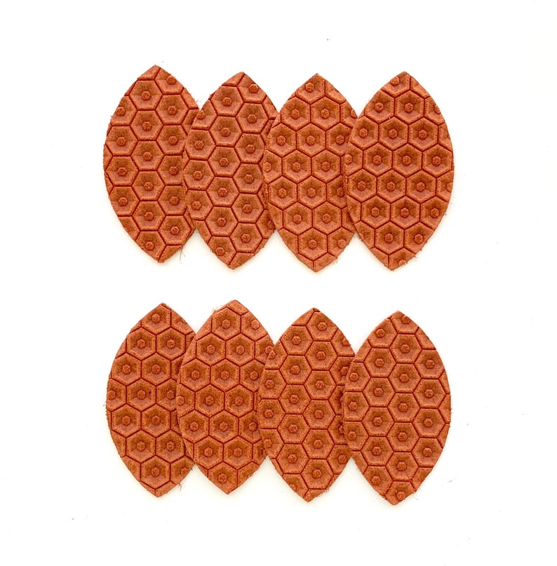 May include: Six brown leather leaves with a honeycomb pattern. The leaves are arranged in two rows of three.