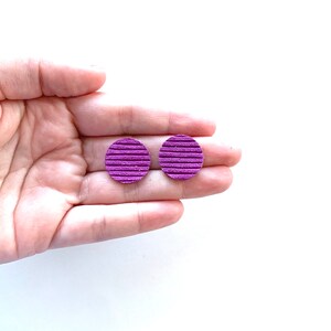 May include: A pair of purple round earrings with a ridged texture.